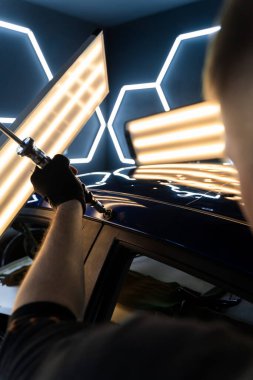 PDR için parlak bir arabanın çatısında çekme aleti kullanmak, basıncı tam olarak ayarlamak. Uzman, metali yeniden boyanmadan eski haline getirmek için ileri çekiş aracı kullanıyor