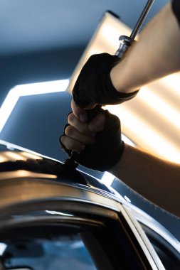 Uzman, metali yeniden boyanmadan eski haline getirmek için ileri çekiş aracı kullanıyor. PDR için parlak bir arabanın çatısında çekme aracı kullanmak, basıncı tam olarak ayarlamak