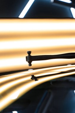 PDR teknisyeni, kaputtaki çukur düzeltmesini kontrol etmek için yansıma lambasına özel bir çekiç tutuyor. Acısız bir araba göçüğü.