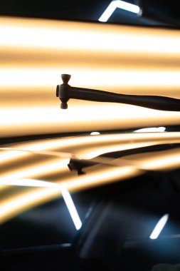 PDR teknisyeni, kaputtaki çukur düzeltmesini kontrol etmek için yansıma lambasına özel bir çekiç tutuyor. Acısız bir araba göçüğü.