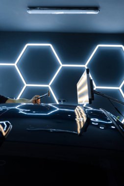 Kontrollü güç, boya hasarı olmadan yüzeyi onarır. PDR sürgülü çekiç, yeniden boyanmamış araba göçüğü. PDR teknisyeni araba panelinden yapışkan şeritler ve çekiç kullanarak bir çukur açtı.