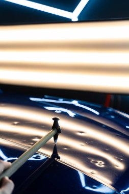 PDR teknisyeni, çarpma aletini ve çekiç kombinasyonunu dolu izlerini düzeltmek için kullanır. Odaklanmış vuruşlar boyaya zarar vermeden metali yeniden hizaladı. Devrilmiş bir aletle kontrol edilen musluklar dolu ile bükülmüş metali yeniden şekillendirir