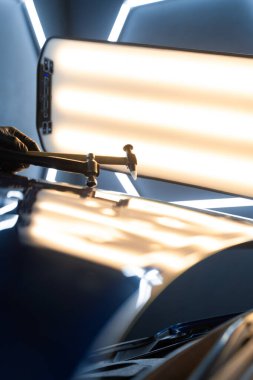 PDR teknisyeni, çarpma aletini ve çekiç kombinasyonunu dolu izlerini düzeltmek için kullanır. Odaklanmış vuruşlar boyaya zarar vermeden metali yeniden hizaladı. Devrilmiş bir aletle kontrol edilen musluklar dolu ile bükülmüş metali yeniden şekillendirir