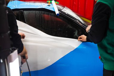 Detaylı merkezdeki araç paneline ıslak plazma yapıştırma. Araba yüzeyini çizik ve ultraviyole ışınlardan korumak için PPF paketleme sırasında koruyucu film katmanı