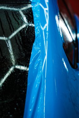Detaylı merkezdeki araç paneline ıslak plazma yapıştırma. Araba yüzeyini çizik ve ultraviyole ışınlardan korumak için PPF paketleme sırasında koruyucu film katmanı