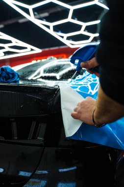Detaylı iş sırasında mavi boya koruma filmini bıçakla kesmek hassas kenarlar sağlar. Detaylı teknisyen mavi PPF 'yi mükemmel bir kondisyon için bir araç paneline yerleştirdi. Bıçakla mavi PPF kesiliyor