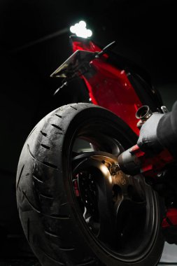 Motosiklet Arka Tekerlek Temizleme. Tamirci, spor bisikletinin arka tekerleğini çıkarmak için yüksek tork çarpma anahtarı kullanır. Arka tekerlek parçalanması yüksek tork anahtarı kullanır