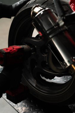 Arka tekerlek parçalanması yüksek tork anahtarı kullanır. Tamirci, spor bisikletinin arka tekerleğini çıkarmak için yüksek tork çarpma anahtarı kullanır. Motosiklet Arka Tekerlek Kaldırma