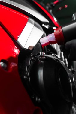 Uygun motor yağını sağlamak için kırmızı bir motorda hassas yağ doldurma operasyonu. Motosiklet yağı doldur. Yüksek performans ve motor ömrünü uzatmak için motor yağını spor motosikletine yerleştirmek