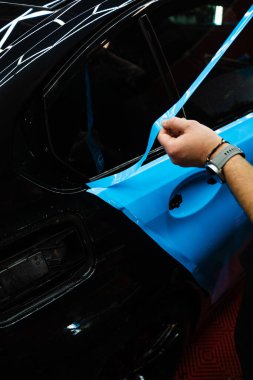 Araba gövdesinde PPF ambalajının hassas kesimi. Hassas PPF ambalaj ve ayrıntılı araba paneli keskin bıçak kullanarak kesinlik ile sarma. Araba tamiri hassas vinil kesim teknikleri gerektirir.