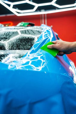 Yeşil bir cam sileceği kullanarak yüksek parlak mavi bir PPF uygulamak, arabanın baloncuksuz ve pürüzsüz bir yüzeyi olmasını sağlar. Mavi PPF yeşil cam sileceği ile uygulanan ayrıntılı araba bitiş ve hasar önlemek için