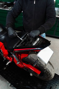 Motosiklet koltuğu kaldırma, elektrik sistemini incelemek için gereklidir. Teknisyen, teşhis için dahili bileşenlere ulaşmak için araçları kullanarak motosiklet koltuğunu dikkatlice kaldırır