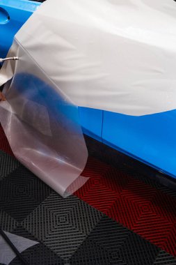 Boya Koruma Filmi PPF Uygulama Süreci. Detaylayıcı, temiz yapışma için panele su uygularken PPF 'den doğrucuyu çıkarır