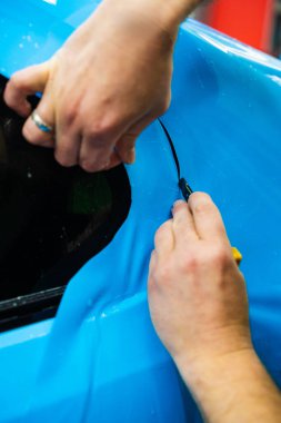 Detaylı teknisyen mavi PPF 'yi mükemmel bir kondisyon için bir araç paneline yerleştirdi. Mavi PPF 'yi bıçakla kesiyorum. Detaylı iş sırasında mavi boya koruma filminin bıçakla kesilmesi hassas kenarları sağlar.