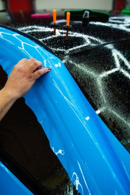 Detaylı teknisyen mavi PPF 'yi mükemmel bir kondisyon için bir araç paneline yerleştirdi. Mavi PPF 'yi bıçakla kesiyorum. Detaylı iş sırasında mavi boya koruma filminin bıçakla kesilmesi hassas kenarları sağlar..