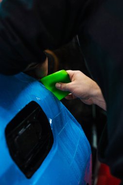 Detaylı merkezdeki araç paneline ıslak plazma yapıştırma. Araba yüzeyini çizik ve ultraviyole ışınlardan korumak için PPF paketleme sırasında koruyucu film katmanı