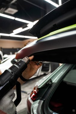 Vinil ambalaj için kullanılan ısı tabancası yapıştırıcıyı aktifleştirir. Isı tabancasıyla arabaya siyah vinil ambalaj uygulamak kesin yapışmayı ve kusursuz yüzey kaplamasını sağlar. Isı Silahıyla Araba Vinili Paketleme