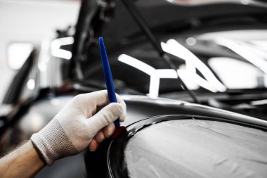 Bir araba paneli kenarına mat siyah sargı uygulamak için kırpma aracı. Trim Tool 'la araba sarma. Araç temizleme, pürüzsüz bitiş için plastik takoz aracı kullanılarak budanma etrafına vinil sarma uygular