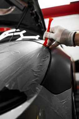 Trim Tool 'la araba sarma. Araç temizleme, pürüzsüz bitiş için plastik takoz aracını kullanarak süsleme etrafına vinil sarma uyguluyor. Bir araba paneli kenarı etrafında mat siyah sargı uygulamak için kırpma aracı