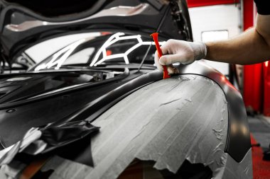 Bir araba paneli kenarına mat siyah sargı uygulamak için kırpma aracı. Trim Tool 'la araba sarma. Araç temizleme, pürüzsüz bitiş için plastik takoz aracı kullanılarak budanma etrafına vinil sarma uygular