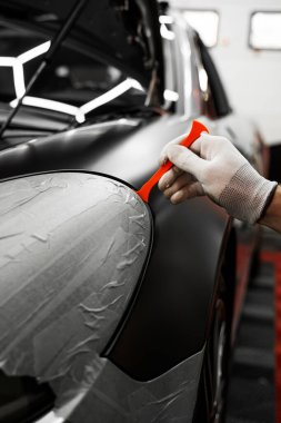 Trim Tool 'la araba sarma. Araç temizleme, pürüzsüz bitiş için plastik takoz aracını kullanarak süsleme etrafına vinil sarma uyguluyor. Bir araba paneli kenarı etrafında mat siyah sargı uygulamak için kırpma aracı