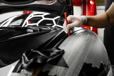 Bir araba paneli kenarına mat siyah sargı uygulamak için kırpma aracı. Trim Tool 'la araba sarma. Araç temizleme, pürüzsüz bitiş için plastik takoz aracı kullanılarak budanma etrafına vinil sarma uygular