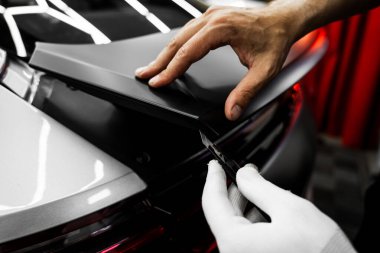 Mükemmel uyum ve temiz görsel sonuçlar için el yapımı vinil kesim. Vinil Uygulaması Detaylandırılıyor. Vinil film, boşluklar ve yırtıklar olmadan pürüzsüz kenarlar sağlamak için keskin bıçakla kesilir.