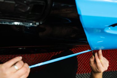 Hassas PPF ambalaj ve ayrıntılı araba paneli keskin bıçak kullanarak kesinlik ile sarma. Araba tamiri hassas vinil kesim teknikleri gerektirir. Araba gövdesinde PPF ambalajının hassas kesimi