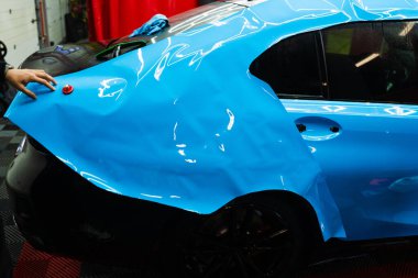 Detaylar hatları sığdırmak için ustalıkla ambalaj uygular ve pürüzsüz, kusursuz bir paket hizalaması sağlar. Tüm detaylar sırasında arabaya PPF ambalajı uygulanıyor. Ayrıntılı merkeze kalın mavi vinil paket kurulumu