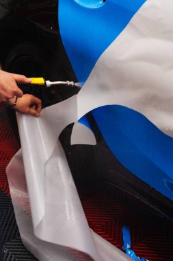 Boya Koruma Filmi PPF Uygulama Süreci. Detaylayıcı, temiz yapışma için panele su uygularken PPF 'den doğrucuyu çıkarır