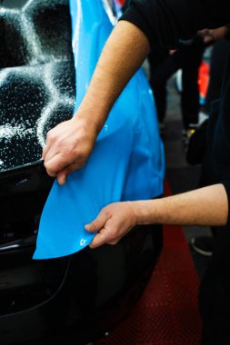 Detaycı, arabanın kaputuna boya koruyucu film gerer ve hatlarıyla mükemmel bir şekilde uyuşur. PPF 'yi araba kaputuna gerdiriyorum ve ayarlıyorum.