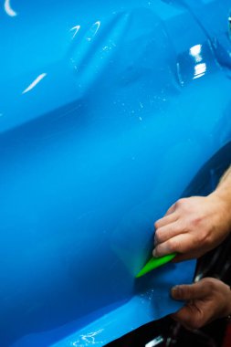 Yeşil bir cam sileceği kullanarak yüksek parlak mavi bir PPF uygulamak, arabanın baloncuksuz ve pürüzsüz bir yüzeyi olmasını sağlar. Mavi PPF yeşil cam sileceği ile uygulanan ayrıntılı araba bitiş ve hasar önlemek için