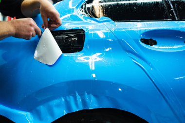 Detaylı teknisyen mavi PPF 'yi mükemmel bir kondisyon için bir araç paneline yerleştirdi. Mavi PPF 'yi bıçakla kesiyorum. Detaylı iş sırasında mavi boya koruma filminin bıçakla kesilmesi hassas kenarları sağlar.