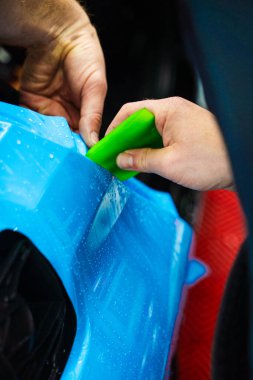 Detaylı merkezdeki araç paneline ıslak plazma yapıştırma. Araba yüzeyini çizik ve ultraviyole ışınlardan korumak için PPF paketleme sırasında koruyucu film katmanı