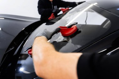 Yeni ön cam kurulum süreci. Aspirasyon asansörlerini kullanarak ön cam kurulumu. İki teknisyen vantilatör kullanarak ön cam kuruyor. Ön cam yerleştirme güvenli bir mühür ve bütünlük sağlar