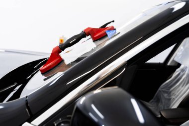 Camı sıkıca tutan kaldırma aletlerini kullanarak ön cam değiştirme. Ön cam teknisyenleri cam çıkarmada elektrikli süpürgeye güvenirler. Emici kaldırıcı kullanarak ön cam kaldırma ve kurulumu.