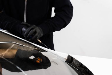 Ön cam kaldırma işlemi özel kesme kablosu ve kazıma aracı kullanılarak yapılıyor. Otomobil teknisyeni ön camı ince tel ve kazıma bıçağı kullanarak ayırıyor. Arabanın ön camını değiştirme işlemi