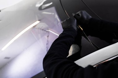 Arabanın ön camını değiştirme işlemi. Ön cam kaldırma işlemi özel kesme kablosu ve kazıma aracı kullanılarak yapılıyor. Otomobil teknisyeni ön camı ince tel ve kazıma bıçağı kullanarak ayırıyor.