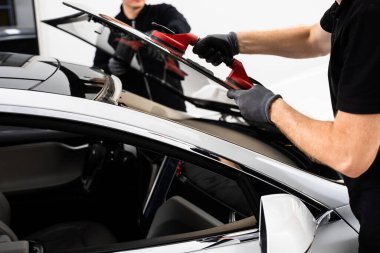 Ön cam yerleştirilmesi, güvenlik ve bütünlük sağlar. Yeni ön cam kurulum süreci. Aspirasyon asansörlerini kullanarak ön cam kurulumu. İki teknisyen aspiratör kullanarak ön camı kuruyor.