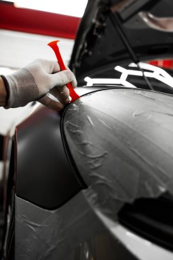 Bir araba paneli kenarına mat siyah sargı uygulamak için kırpma aracı. Trim Tool 'la araba sarma. Araç temizleme, pürüzsüz bitiş için plastik takoz aracı kullanılarak budanma etrafına vinil sarma uygular