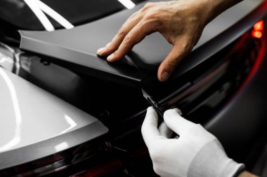 Mükemmel uyum ve temiz görsel sonuçlar için el yapımı vinil kesim. Vinil Uygulaması Detaylandırılıyor. Vinil film, boşluklar ve yırtıklar olmadan pürüzsüz kenarlar sağlamak için keskin bıçakla kesilir.