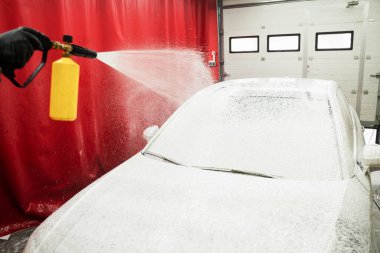 Araba Köpürtme Sahnesi. Yüksek basınçlı kar köpüğü uygulaması derin bir temizlik sağlar ve araba yüzeyindeki kiri yumuşatır. Araba ilk yıkama aşamasında yoğun kar köpüğüyle kaplanır.