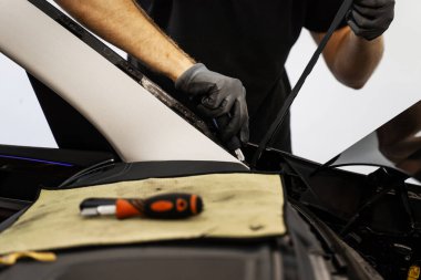 Ön cam çıkarıldıktan sonra artık yapıştırıcıyı çıkarıyorum. Teknisyen cam söktükten sonra yapışkan kalıntılarını kazıdı. Yapıştırıcının temiz çıkarılması doğru ön camın yeniden mühürlenmesi için hayati önem taşıyor.