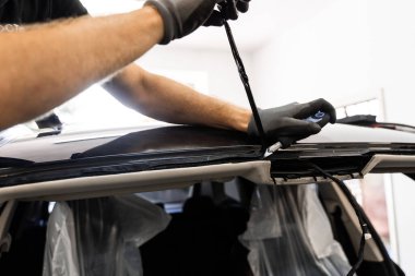 Ön cam çıkarıldıktan sonra artık yapıştırıcıyı çıkarıyorum. Teknisyen cam söktükten sonra yapışkan kalıntılarını kazıdı. Yapıştırıcının temiz çıkarılması doğru ön camın yeniden mühürlenmesi için hayati önem taşıyor.