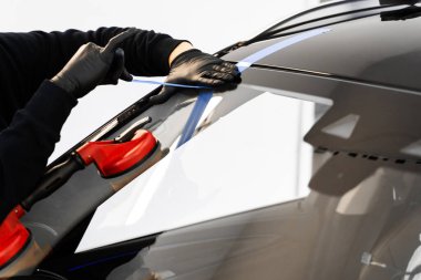 Camı sıkıca tutan kaldırma aletlerini kullanarak ön cam değiştirme. Ön cam teknisyenleri cam çıkarmada elektrikli süpürgeye güvenirler. Emici kaldırıcı kullanarak ön cam kaldırma ve kurulumu.