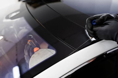 Arabanın ön camını değiştirme işlemi. Ön cam kaldırma işlemi özel kesme kablosu ve kazıma aracı kullanılarak yapılıyor. Otomobil teknisyeni ön camı ince tel ve kazıma bıçağı kullanarak ayırıyor.