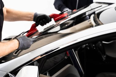 Ön cam yerleştirilmesi, güvenlik ve bütünlük sağlar. Yeni ön cam kurulum süreci. Aspirasyon asansörlerini kullanarak ön cam kurulumu. İki teknisyen aspiratör kullanarak ön camı kuruyor.