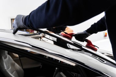 İki teknisyen vantilatör kullanarak ön cam kuruyor. Ön cam yerleştirilmesi, güvenlik ve bütünlük sağlar. Yeni ön cam kurulum süreci. Ön cam kurulumu Aspirasyon Kaldırıcıları Kullanılarak