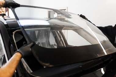 Profesyonel cam değişimine hazırlanmak için kırık ön cam çıkarımı. Kırık camların çıkarılması, yeniden görünürlük ve yapısal güvenliğin sağlanması açısından çok önemli.