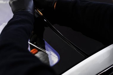 Otomobil teknisyeni ön camı ince tel ve kazıma bıçağı kullanarak ayırıyor. Arabanın ön camını değiştirme işlemi. Özel kesme kablosu ve kazıma aracı kullanılarak ön cam kaldırma işlemi devam ediyor